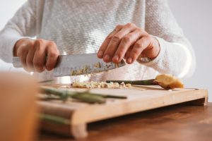 person holding knife slicing vegetable